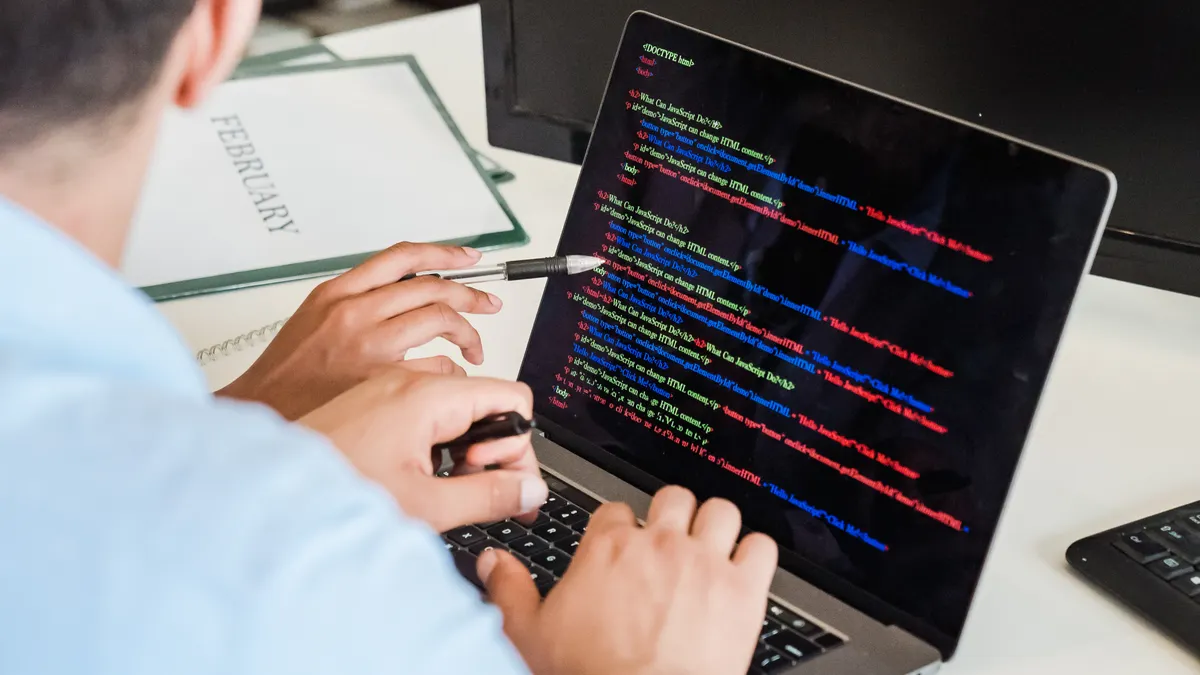 Close-up of a developer writing application code on a laptop