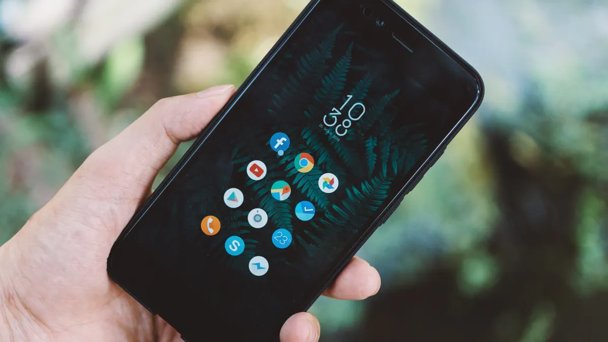 Hand holding a smartphone showing a mobile app home screen